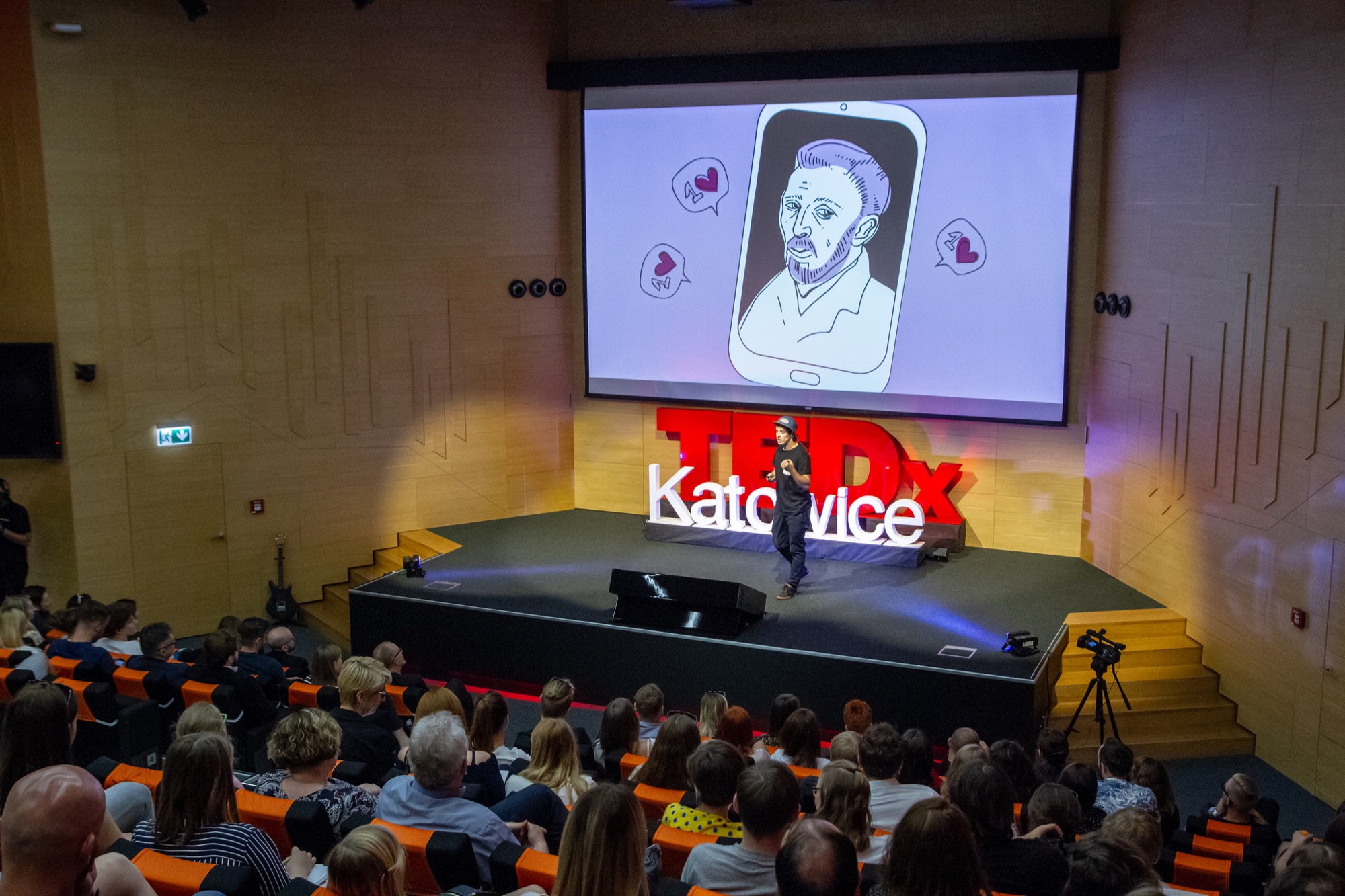 Bartek Sibiga speaking on stage at TEDx Katowice before a full audience